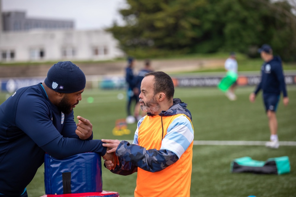 Un encadrant et un participant lors d’un entraînement de rugby adapté